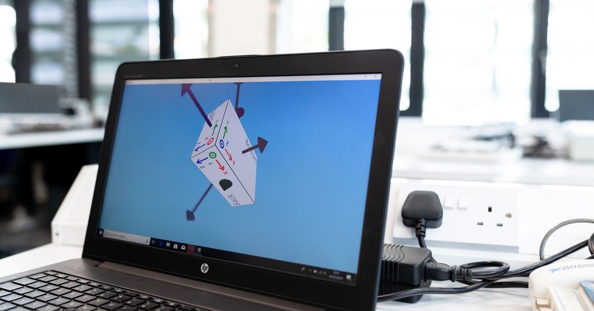 A laptop screen showing 3D design software in a studio workspace