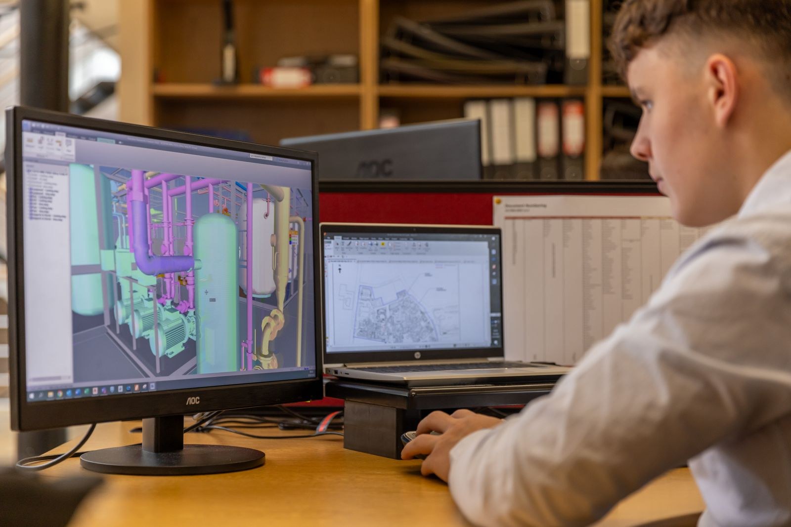 Dual monitors showing 3D software during a transfer of work