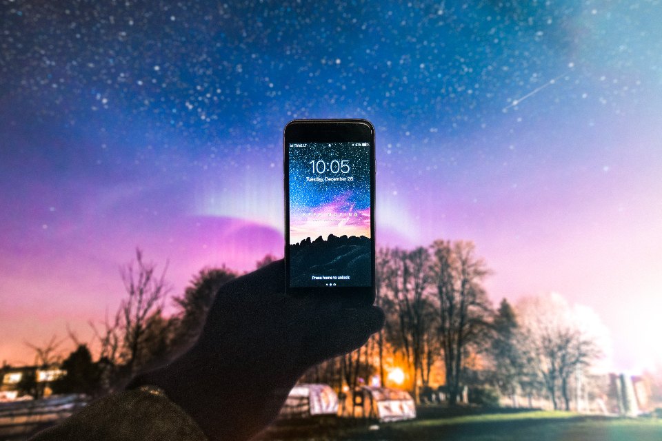 A hand holding up a phone against a starry sky