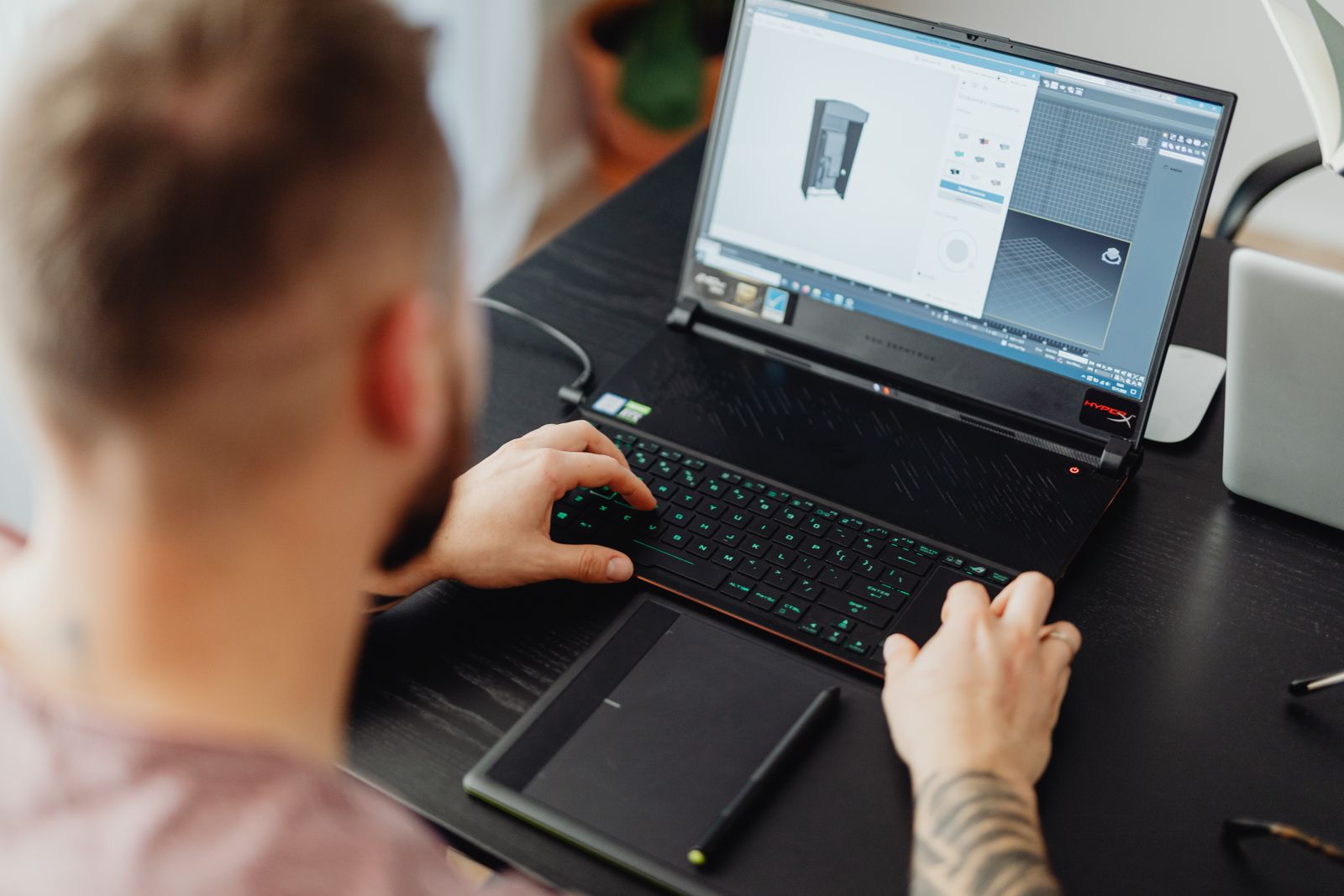 An animator working on 3D design with a laptop and tablet