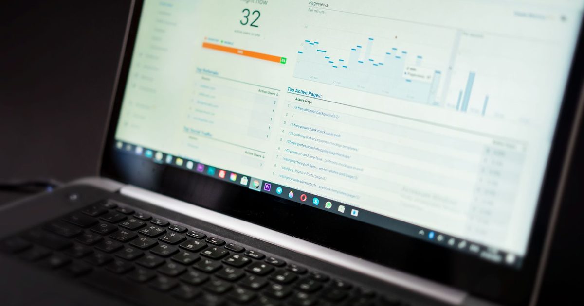 A laptop showing a website analytics dashboard with charts on a desk