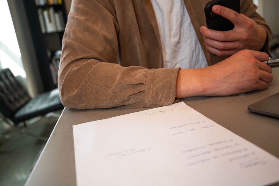 A person holding a phone at a desk with a printed document in front of them