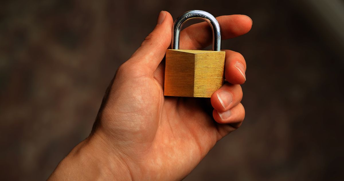 A hand holding a padlock, representing an encrypted PDF