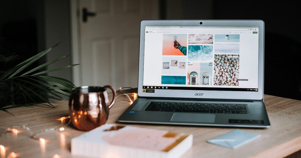Un ordinateur portable ouvert sur un bureau en bois à côté d'une tasse de café