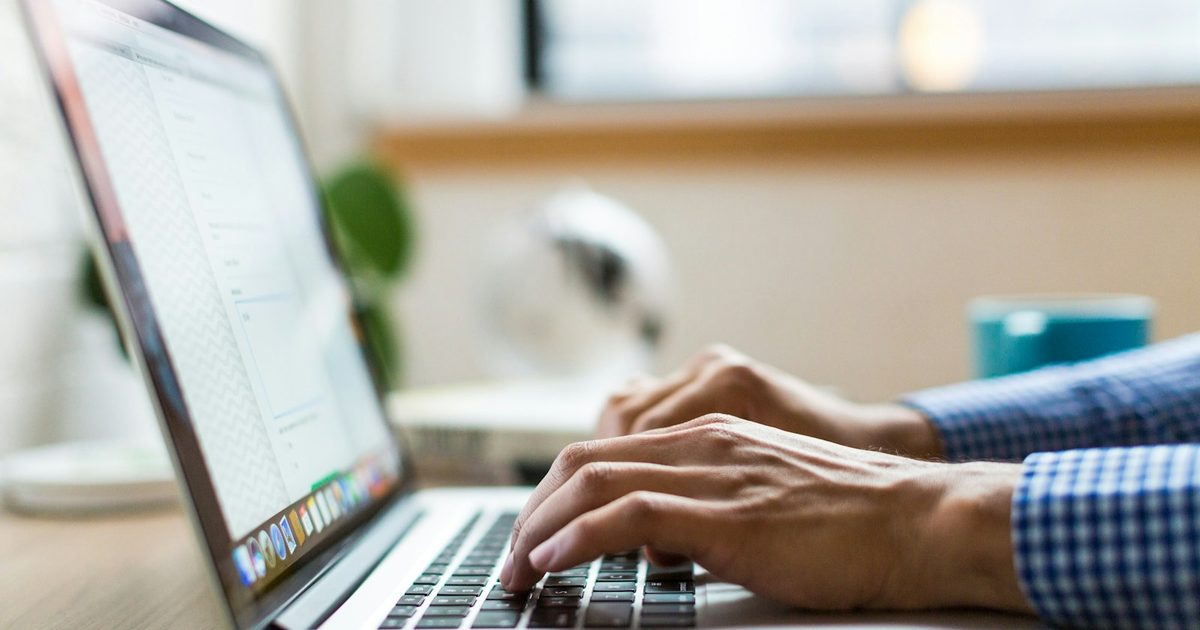 Person typing on a laptop keyboard while drafting on screen