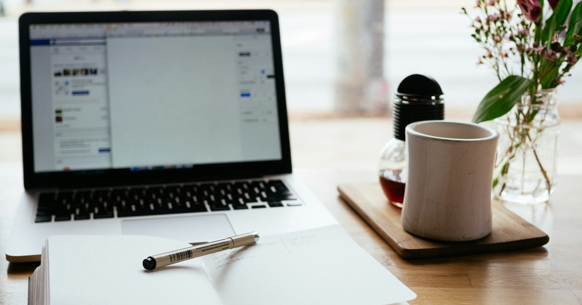 A laptop next to an open notebook on a desk