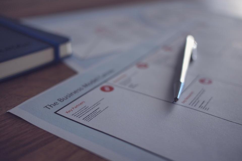 A printed document and a pen on a wooden desk
