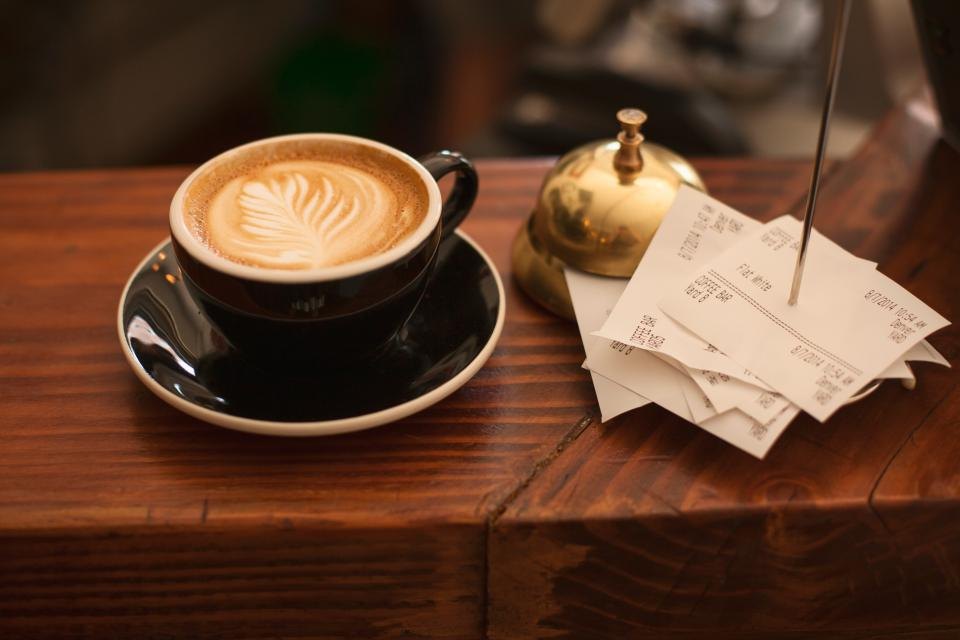 Paper receipts beside a coffee cup on a cafe counter