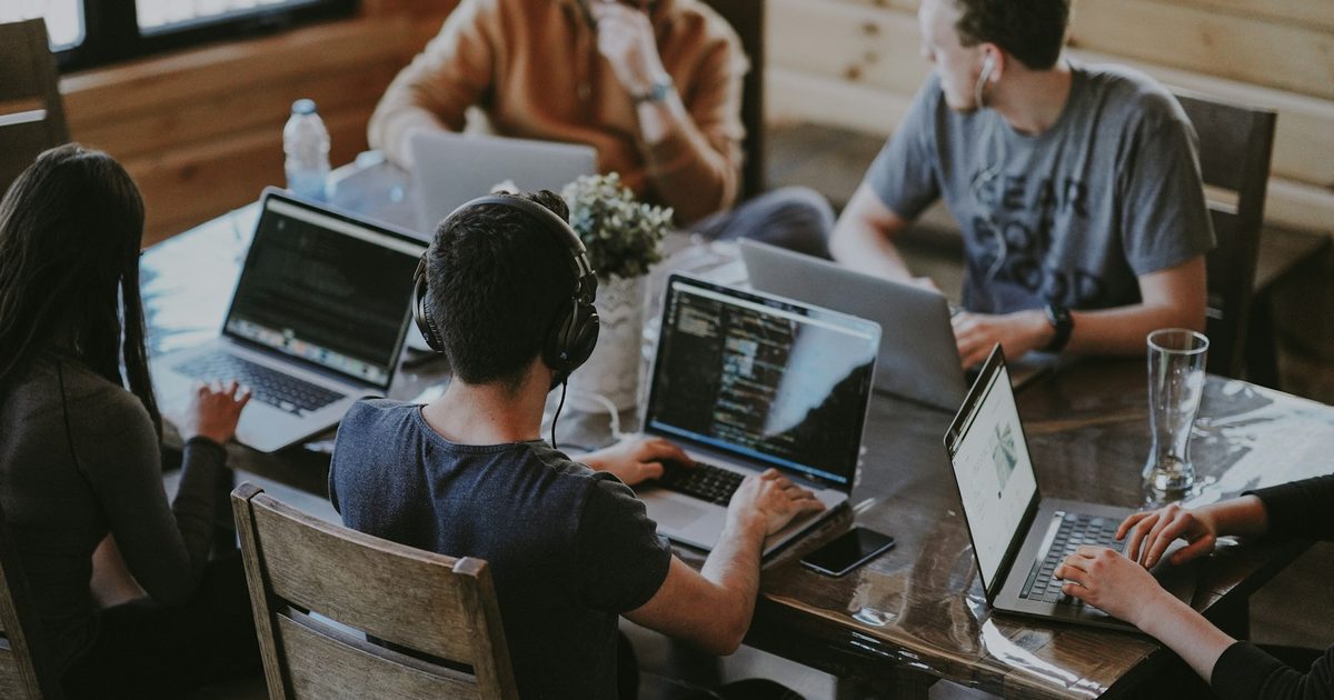 Une équipe qui collabore autour d'ordinateurs portables sur une table partagée