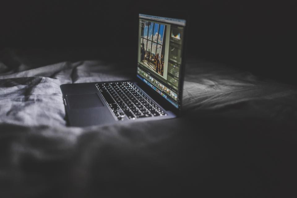 A laptop on a desk at night, screen glowing