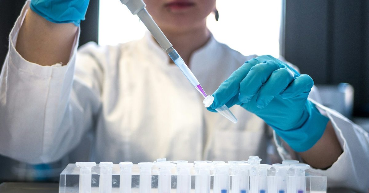 A scientist using a pipette with test tubes in a laboratory