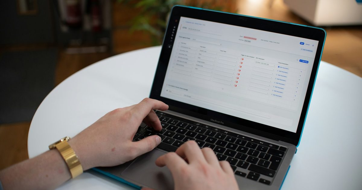 Hands typing on a laptop showing a spreadsheet, representing workflow automation